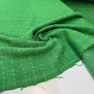 a close-up view of a green tweed fabric with a distinctive woven pattern.