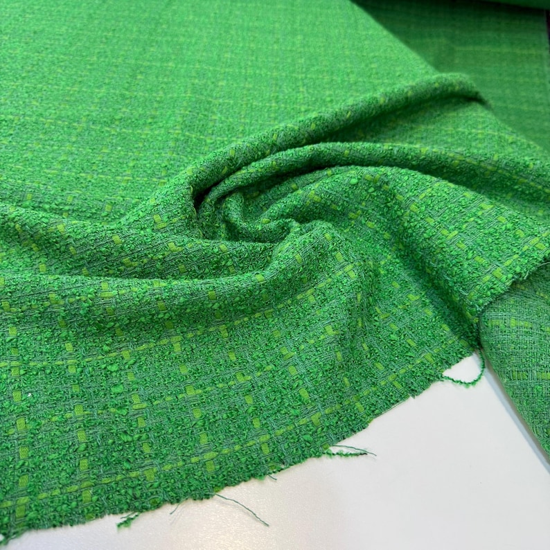 a close-up view of a green tweed fabric with a distinctive woven pattern.