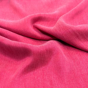 a close-up view of a bright pink fabric, with a slightly wrinkled texture.