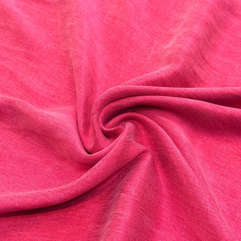 a close-up view of a vibrant pink fabric, with a noticeable curl and texture.
