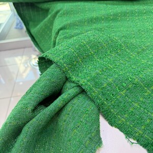 a close-up view of a green tweed fabric, with a textured and woven appearance.