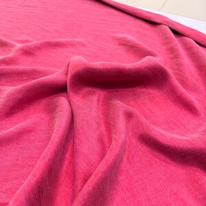 a close-up view of a crumpled, pink fabric, possibly a piece of clothing or a textile.