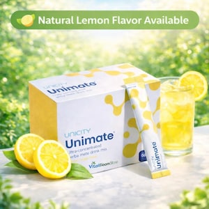 Op de afbeelding: Een witte doos met gele accenten van Unicity Unimate ultra-geconcentreerde yerba mate drankmix met merknaam. Een zakje van de mix en een glas van de drank met een citroenschijfje zijn ook afgebeeld. Twee citroenhelften staan op de voorgrond.