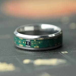 Puede incluir: Una taza de cerámica blanca con un asa negra y el texto "But First, Coffee" en negro, con una fuente de estilo manuscrito. La taza está sobre una superficie blanca.