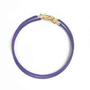 May include: A pair of purple hoop earrings with gold clasps.
