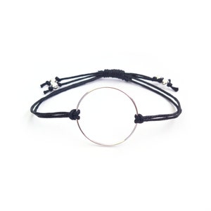 May include: A black string bracelet with a silver circle charm.