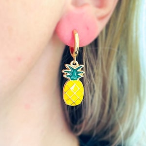 May include: Gold hoop earrings with a yellow and green enamel pineapple charm.