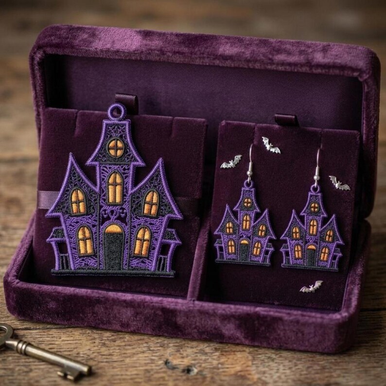 Puede incluir: Un joyero de terciopelo morado que contiene un gran colgante bordado de casa encantada y un par de pendientes a juego, acompa&ntilde;ados de peque&ntilde;os dijes de murci&eacute;lago plateados, todo con intrincados hilos morados y naranjas.