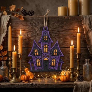 Puede incluir: Un adorno de casa encantada bordado en morado y negro con un lazo de cuerda de yute para colgar. El dise&ntilde;o presenta costuras intrincadas, m&uacute;ltiples techos puntiagudos y ventanas iluminadas en amarillo sobre un fondo de madera r&uacute;stica.