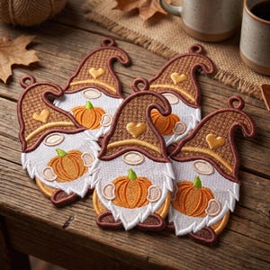May include: Four embroidered gnome ornaments featuring brown hats with gold heart accents and white beards. Each gnome holds an orange pumpkin with green stems. The ornaments have a small loop at the top for hanging and are crafted with detailed stitching.