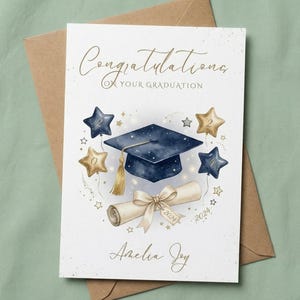 Puede incluir: Una tarjeta de graduación con un birrete azul marino, una borla dorada y globos en forma de estrella. La tarjeta dice "Felicidades por tu graduación" en letras doradas, con el nombre del graduado y el año 2024.