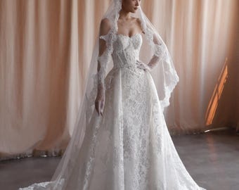 Vestido de novia de encaje estilo sirena, sin tirantes, con corsé, sobrefalda desmontable y velo.