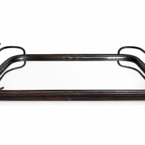 May include: A rectangular mirrored tray with a dark, weathered metal frame. The tray features two curved metal handles, each topped with a small, sculpted bird figure. It stands on four small, rounded metal feet at the corners of the base.