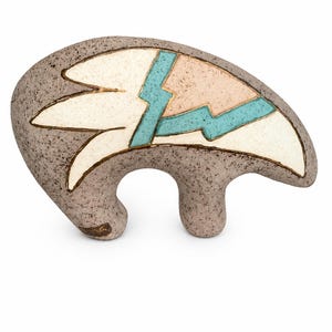 May include: A ceramic bear figurine with a speckled gray finish. The body features a decorative inlay design in cream, light pink, and turquoise, outlined with thin gold lines. The sculpture has a rounded, stylized form with two legs.