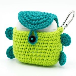 May include: A handmade crochet AirPod case in lime green and teal. The case has a flap closure with a black button and a silver carabiner clip. The case is designed to protect and carry wireless earbuds.