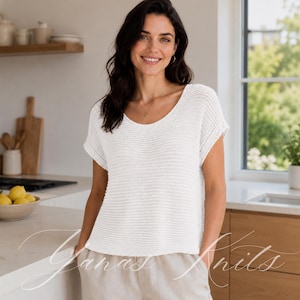 Peut inclure: Un haut en tricot blanc à manches courtes avec une large encolure dégagée et un motif de points horizontaux texturés. Le vêtement présente une coupe décontractée avec des manches à revers et un ourlet droit, en maille légère et respirante.