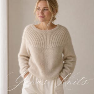 Può includere: Un maglione a maniche lunghe color crema con scollo rotondo e un design a sprone in maglia a coste. Il capo presenta una consistenza morbida e soffice su tutto il corpo e le maniche, con polsini a coste e un orlo abbinato in vita.