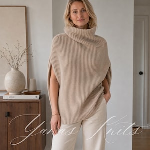 May include: A beige ribbed knit poncho with a high turtleneck collar and open sides. The garment features a vertical knit pattern and a relaxed fit, paired with light-colored trousers. The design provides a structured yet comfortable silhouette.