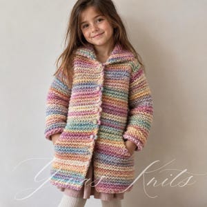 Könnte beinhalten: Eine langärmelige Strickjacke mit Knopfleiste, grober Strickstruktur und horizontalen Streifen in Pastelltönen wie Rosa, Gelb, Blau und Violett. Das Kleidungsstück verfügt über einen breiten Kragen, zwei Vordertaschen und kleine, runde, bunte Knöpfe.