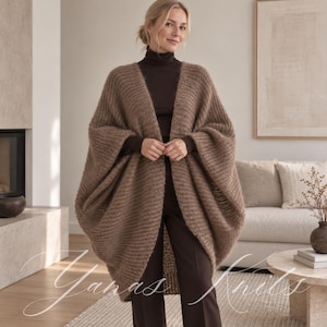 Op de afbeelding: Een bruin, aan de voorzijde open, oversized gebreid vest met een geribbelde textuur en wijde mouwen. Het kledingstuk wordt gedragen over een donkerbruine coltrui en een donkerbruine broek. De tekst Yanas Knits staat onderaan de afbeelding.