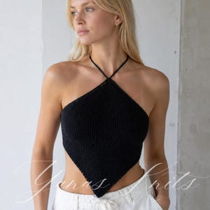 Könnte beinhalten: Ein schwarzes Strick-Neckholder-Top mit dreieckiger Silhouette und spitz zulaufendem Saum. Das Kleidungsstück ist in einem feinen, strukturierten Strickmuster gefertigt und verfügt über dünne, schwarze Träger, die im Nacken gebunden werden.