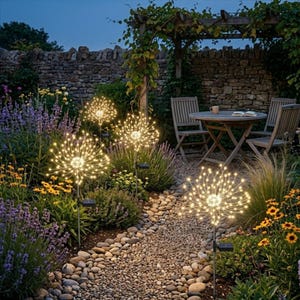 Op de afbeelding: Vier bolvormige solarlampen voor in de tuin met dunne, uitstralende draadstelen voorzien van warmwitte ledlampjes. Elke lamp is gemonteerd op een slanke metalen staak met een klein, rechthoekig zonnepaneel bevestigd aan de onderzijde.