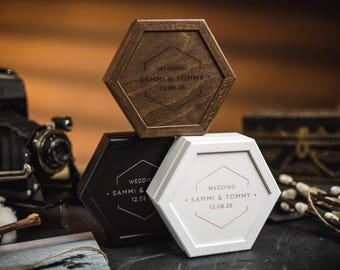 Puede incluir: Tres cajas hexagonales de madera en marrón, negro y blanco, apiladas. Cada caja tiene un diseño geométrico y el texto "WEDDING SAMMI & TOMMY 12.08.26".