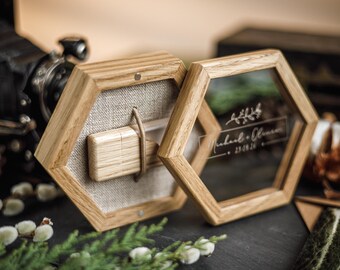 Puede incluir: Dos cajas hexagonales de madera con cristal transparente y respaldo de lino. Una caja contiene un pequeño bloque de madera. La otra caja tiene los nombres "Michael & Olivia" y la fecha "23.09.20" grabados en el cristal. Decoración de boda.