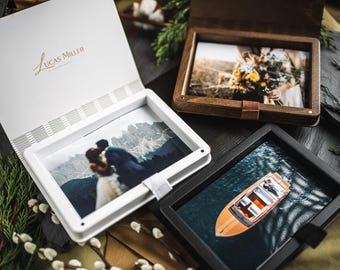 Puede incluir: Una colección de fotografías enmarcadas, que incluye una caja de fotos blanca con el texto "Lucas Miller" en escritura dorada. Los marcos son negros, blancos y de madera, cada uno con una imagen diferente, incluido un barco en el agua y una pareja.