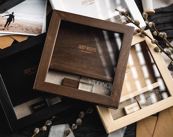 Puede incluir: Tres cajas de madera con tapas de cristal, en tonos negro, marrón y madera clara. Las cajas tienen un diseño de marco cuadrado y contienen un interior de lino. El texto "WEDDING DAY" es visible en una etiqueta. Cajas para fotografía.