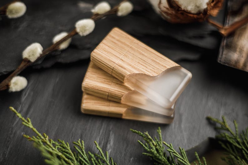 May include: Three rectangular USB flash drives stacked together, each featuring a natural light brown wood grain body paired with a smooth, translucent frosted resin cap that covers one end of the device.