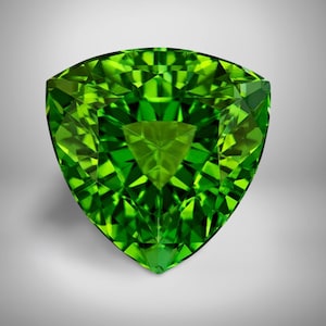 May include: A faceted, triangular-shaped gemstone with a vibrant, bright green color. The gem has a complex, multi-faceted design that reflects light, creating a sparkling effect. The gemstone is set against a neutral background.