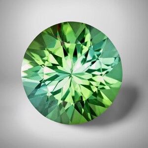May include: A round, faceted gemstone with a vibrant green hue. The gem's surface is a mosaic of triangular facets, creating a play of light and shadow. The gemstone is set against a soft, neutral background, highlighting its brilliance.