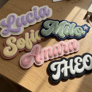 Puede incluir: Cinco parches de nombre personalizados con letras texturizadas en relieve en colores pastel y llamativos. Los nombres Lucia, Sofia, Milo, Amara y THEO se muestran en fuentes cursivas y de bloque, sobre un fondo de fieltro contrastante.