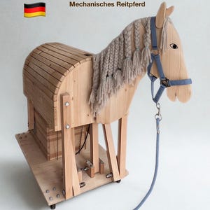 Könnte beinhalten: Ein mechanisches Holzpferd in heller Holzoptik mit geflochtener beiger Wollmähne, blauem Halfter und passendem Führstrick. Der Text BAUE DEIN EIGENES Mechanisches Reitpferd Vollständige Bauanleitung ist oben und unten zu sehen.