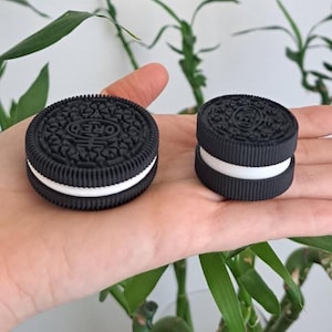 Puede incluir: Dos réplicas de galletas tipo sándwich redondas, en blanco y negro, con el texto OREO en relieve en la superficie superior. Las galletas tienen un borde exterior negro texturizado y una capa central blanca lisa, presentadas en dos tamaños.