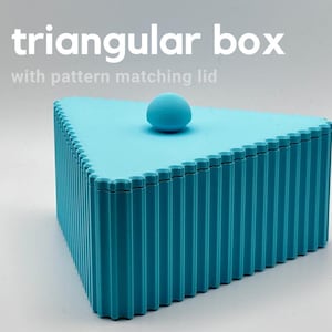 May include: A bright cyan triangular box with a scalloped edge and a matching lid featuring a small spherical handle. The text "triangular box with pattern matching lid" is printed in white above the object on a plain light background.