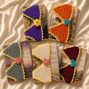 May include: Five crochet book sleeves in purple, orange, gray, cream, and maroon, each featuring a yellow scalloped border and a small crocheted flower in the center. The sleeves are placed over individual books with various cover illustrations.