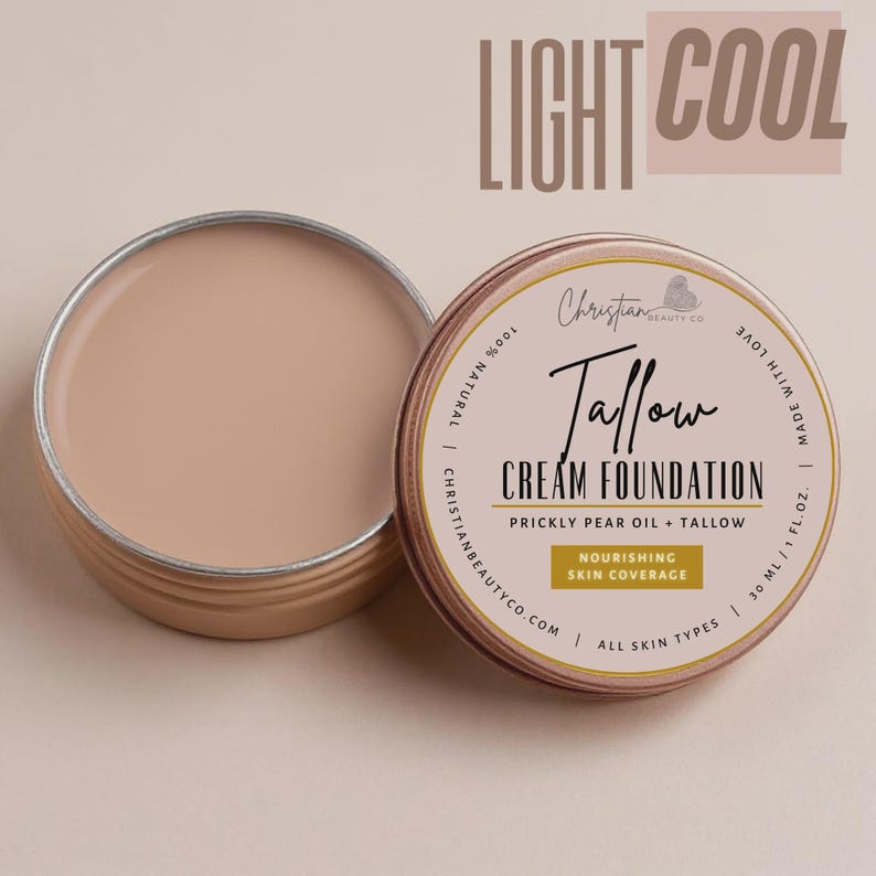 May include: An open, round, light brown container of cream foundation next to a closed container. The closed container has a label with the text "Tallow Cream Foundation" and "Nourishing Skin Coverage". The text "Light Cool" is at the top.