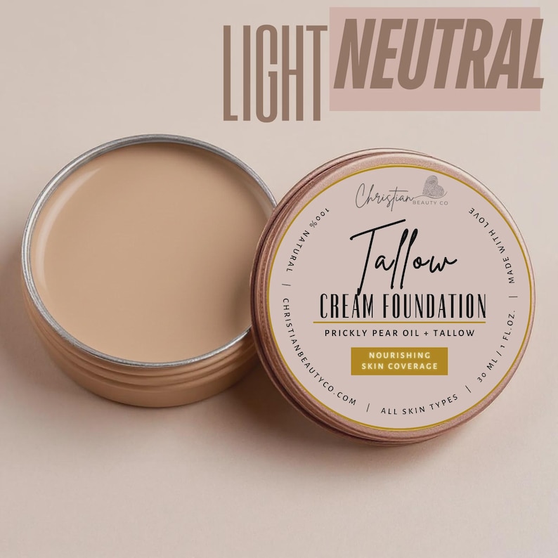 May include: A light neutral cream foundation in a round, open tin. The tin is tan with a gold rim and has the text "Tallow Cream Foundation" and "Nourishing Skin Coverage". The text "Light Neutral" is at the top.