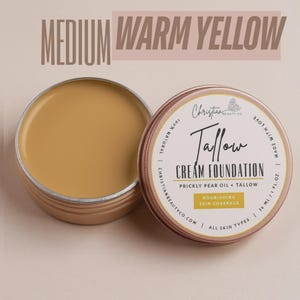 May include: Open tin of medium warm yellow Tallow Cream Foundation by Christian Beauty Co. The product is made with prickly pear oil and tallow, and is designed for nourishing skin coverage. The text "Medium Warm Yellow" is at the top.