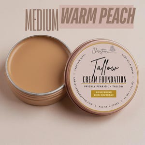 May include: A tin of "Medium Warm Peach" Tallow Cream Foundation, with the lid off, revealing the product. The label reads "Christian Beauty Co" and "Nourishing Skin Coverage". The product is for all skin types and is 30 ml / 1 fl oz.