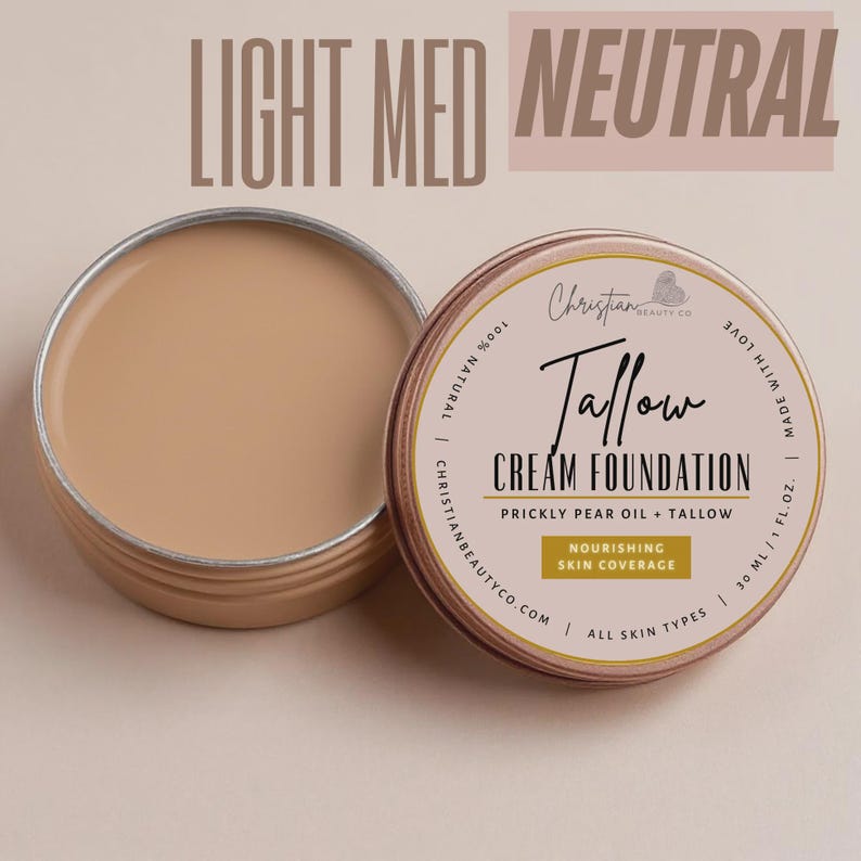 May include: Open tin of light-medium neutral-toned cream foundation next to a closed tin. The label reads "Tallow Cream Foundation" with "Prickly Pear Oil + Tallow" and "Nourishing Skin Coverage" text. The product is 100% natural and suitable for all skin types.