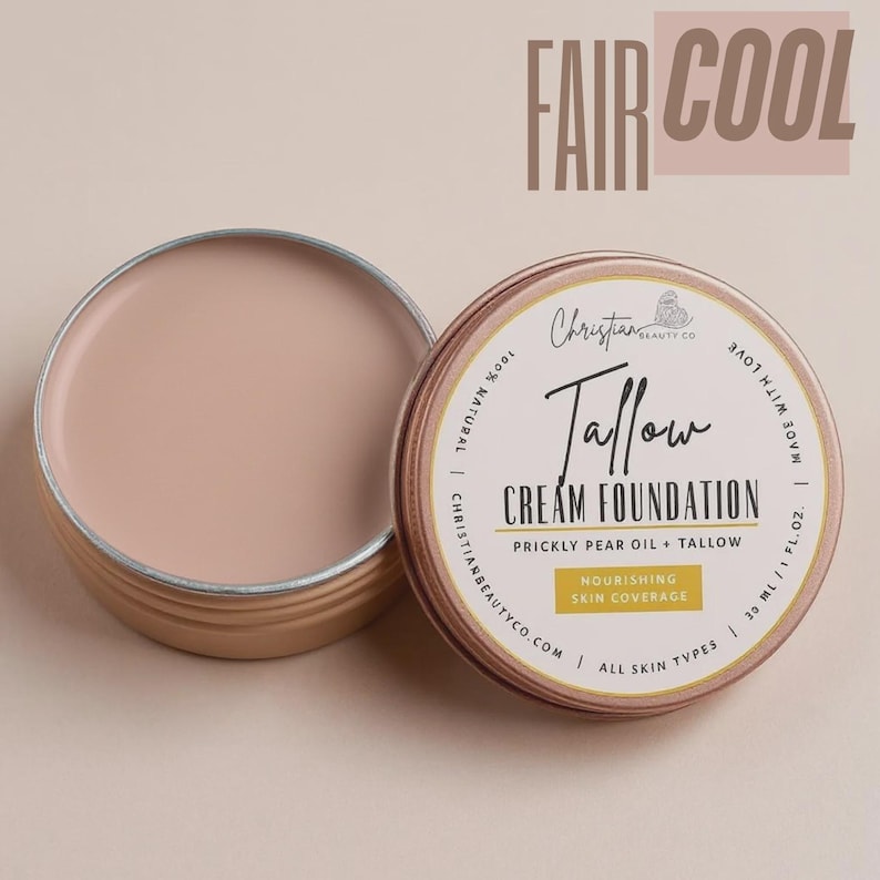 May include: A round, open tin of Fair Cool Tallow Cream Foundation, next to a closed tin. The foundation is a light beige color. The closed tin has a label with the text "Tallow Cream Foundation" and "Prickly Pear Oil + Tallow". The text "Fair Cool" is at the top.