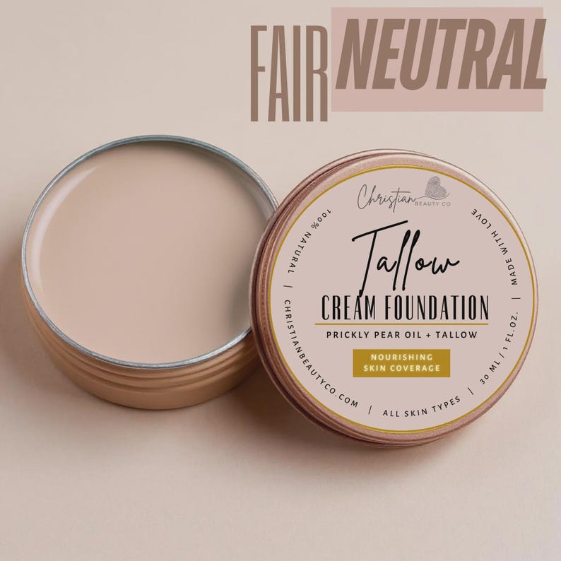 May include: Open, round, metal tin of Fair Neutral Tallow Cream Foundation. The lid is off, revealing the creamy product. The label reads "Tallow Cream Foundation" with "Prickly Pear Oil + Tallow" and "Nourishing Skin Coverage".