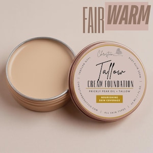 May include: Open, round, metal container of cream foundation with the text "Tallow Cream Foundation" and "Nourishing Skin Coverage". The foundation is a fair, warm tone. The container is labeled "Christian Beauty Co."