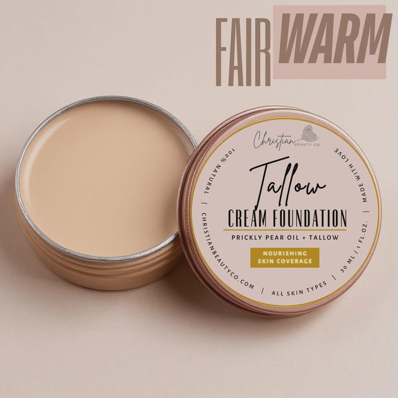 May include: Open, round, metal container of cream foundation with the text "Tallow Cream Foundation" and "Nourishing Skin Coverage". The foundation is a fair, warm tone. The container is labeled "Christian Beauty Co."