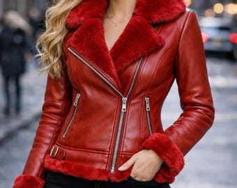 May include: A red leather jacket featuring a wide faux fur collar, matching red faux fur trim at the cuffs and hem, silver-toned metal zippers on the front and pockets, and a side buckle detail at the waist, paired with black pants.