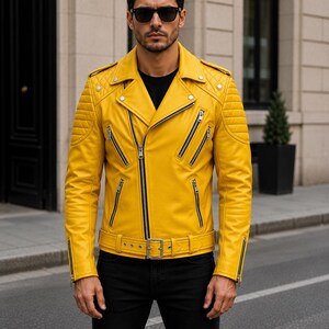Man wearing yellow leather biker jacket with quilted sleeves, asymmetrical front zipper and belted waist in an urban evening setting.