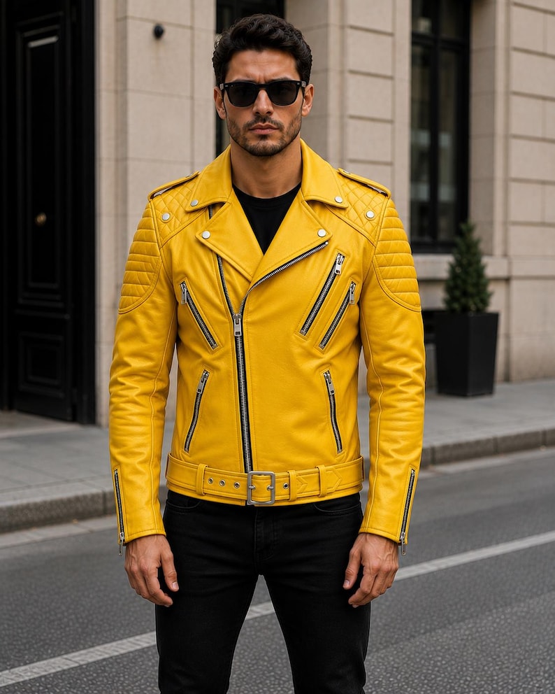 Man wearing yellow leather biker jacket with quilted sleeves, asymmetrical front zipper and belted waist in an urban evening setting.